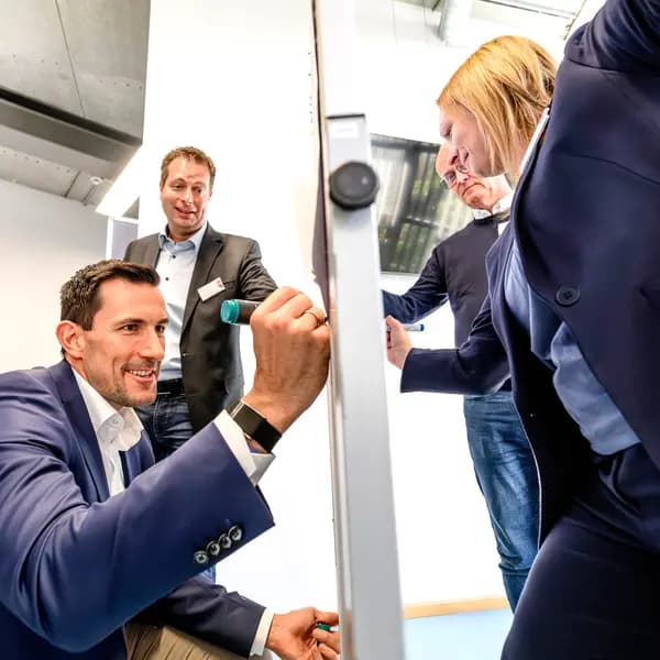 Kolleg:innen arbeiten gemeinsam an einem Whiteboard