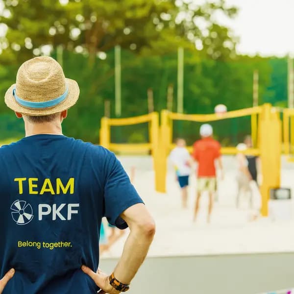 Kollege im Team-PKF-Shirt beobachtet ein Beachvolleyballspiel