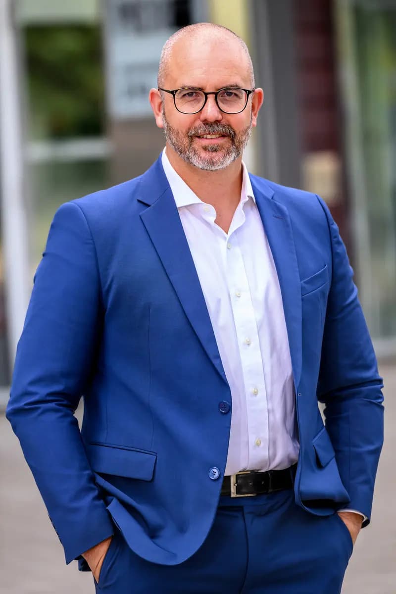 Porträt von Heiko Schöning im blauen Anzug vor einem Gebäude